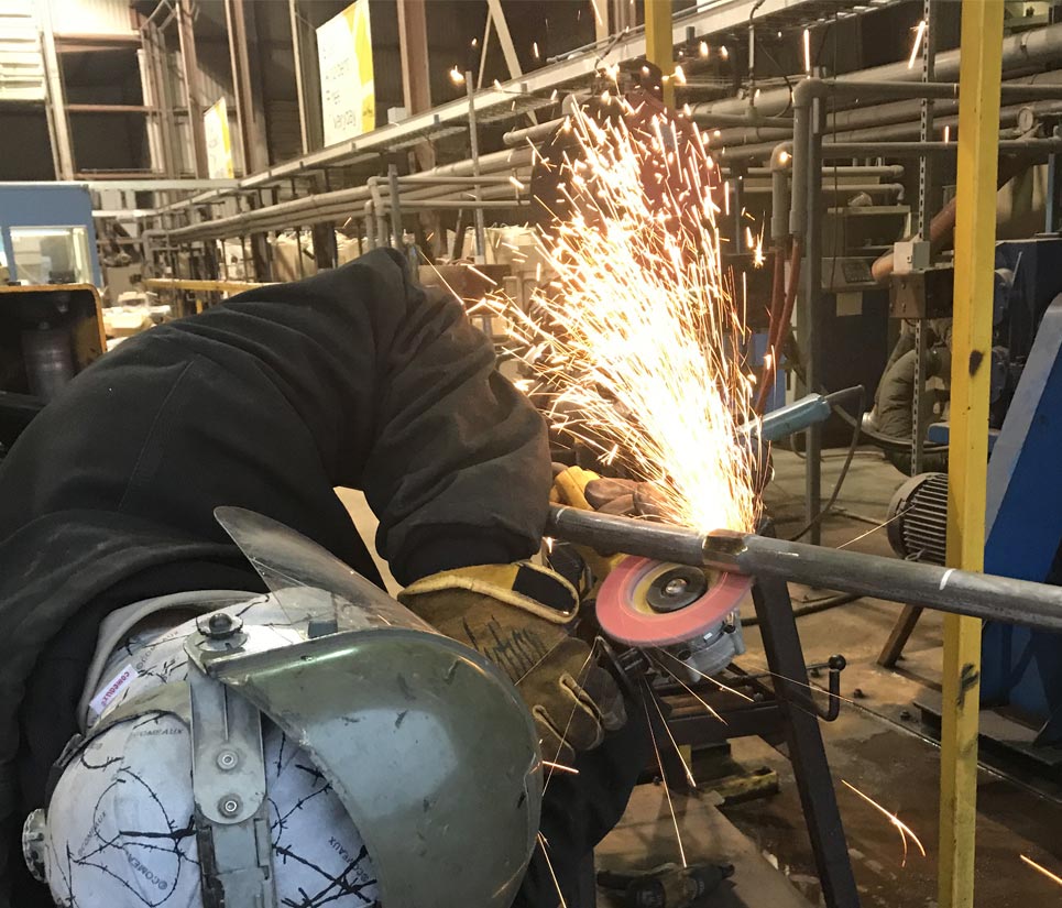 shop worker grinding steal pipe